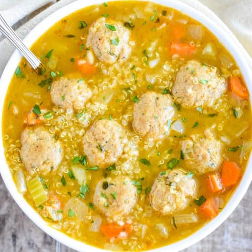 closeup overhead of quinoa soup in white bowl with spoon in it