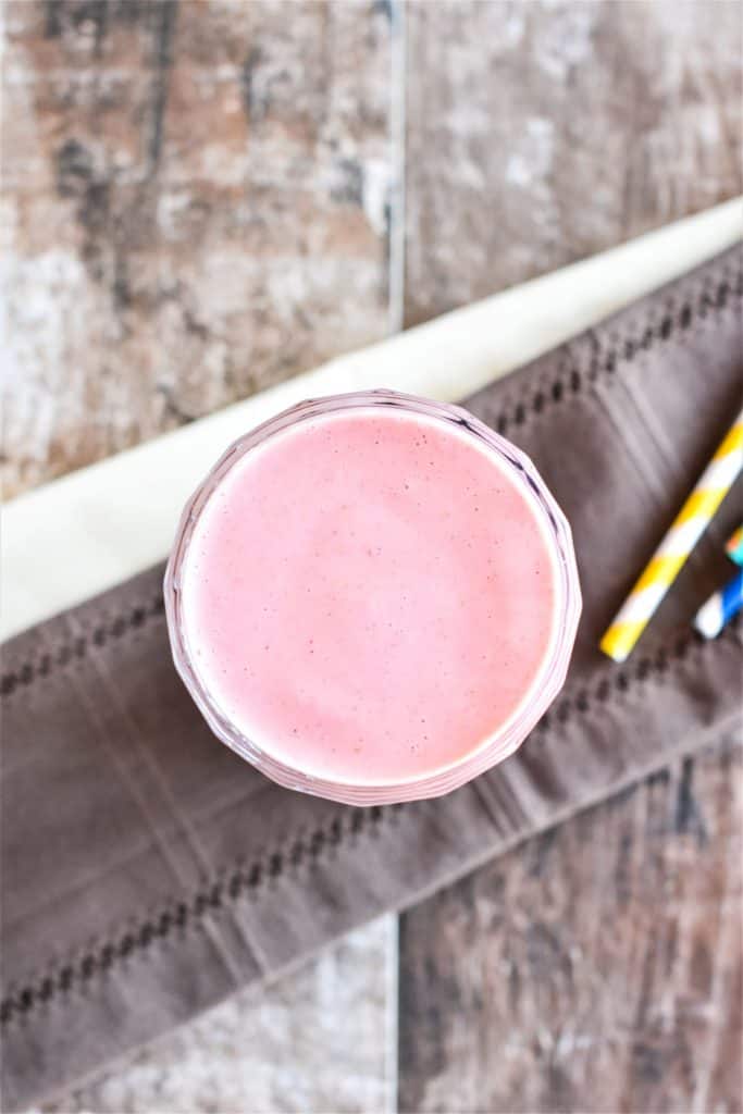 overhead of smoothie in a glass with parts of straws off to the right side