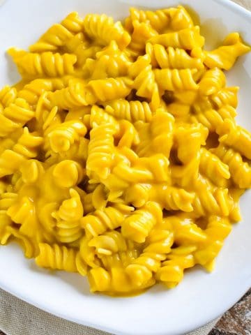 close-up overhead of pasta in pumpkin cheese sauce on white plate