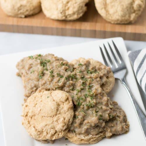 overhead of serving of biscuits and gravy on a white plate with a fork.