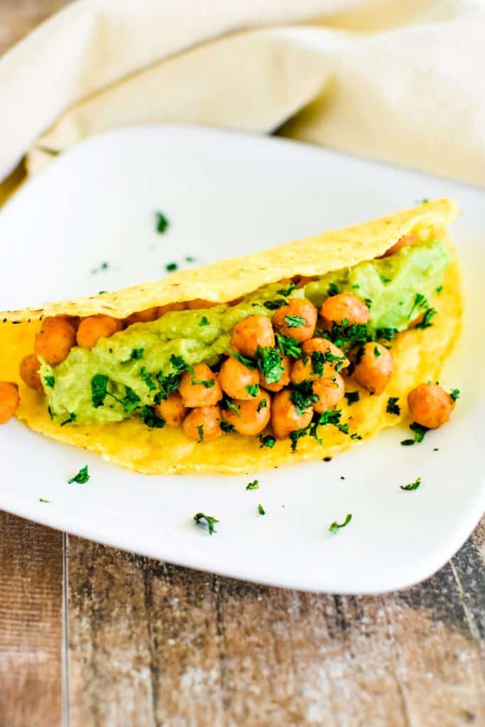 one chickpea taco on white plate with open side facing to the right.