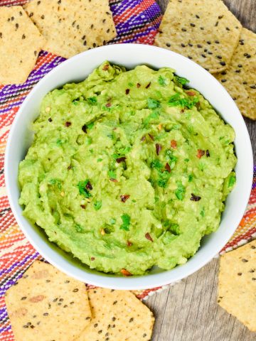 close-up overhead of guacamole in white bowl.