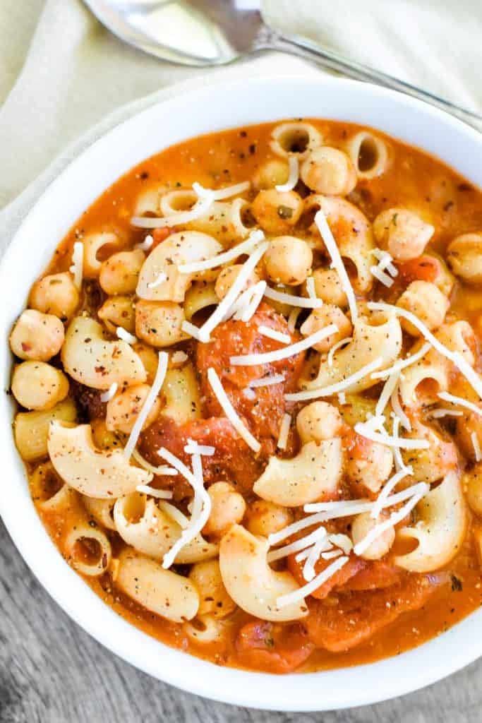 overhead of pasta and chickpeas in white bowl with part of right side cut off