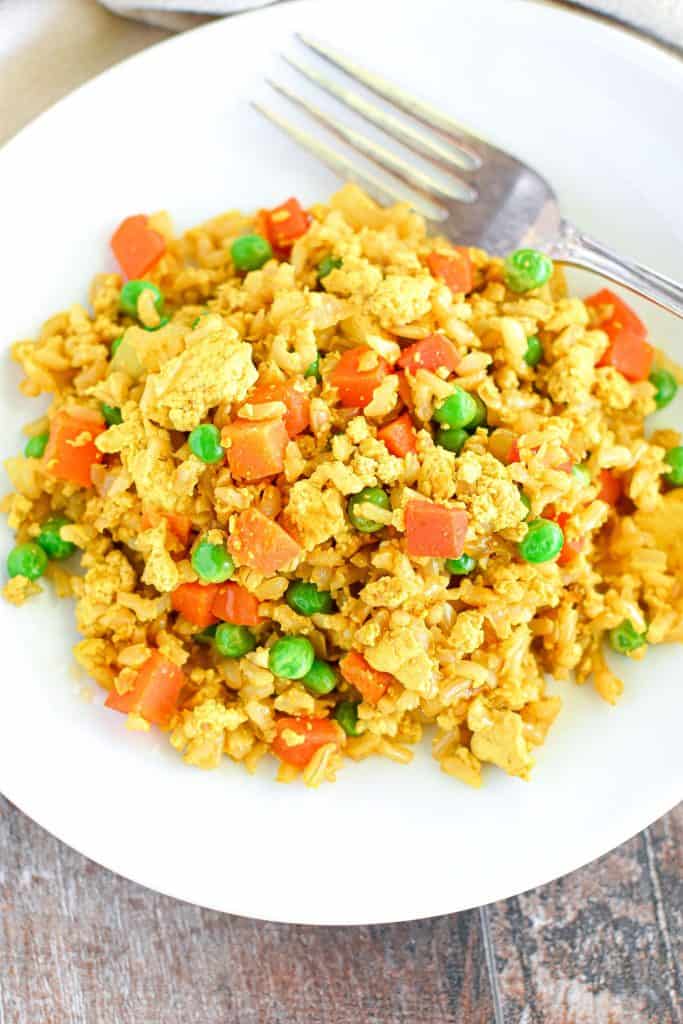 overhead of vegan fried rice on white plate with a fork.