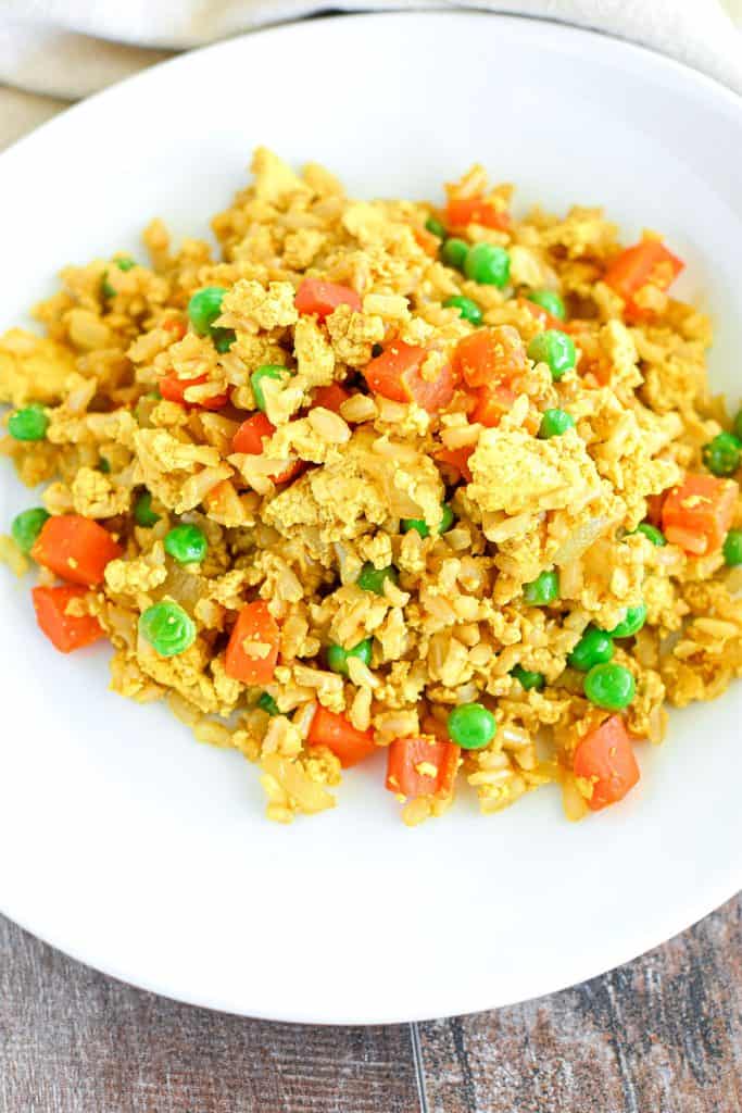 fried rice on a white plate with kitchen towel behind it.