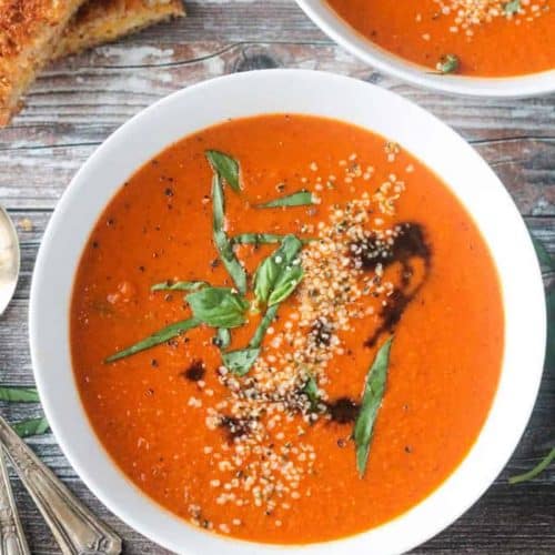 overhead of tomato soup in white bowl with another one partially in view behind it.