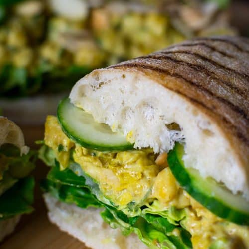 close-up half of chickpea sandwich on a wooden board.