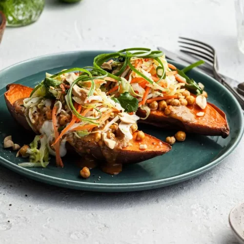 Thai peanut sweet potatoes on a plate with fork and knife on side.