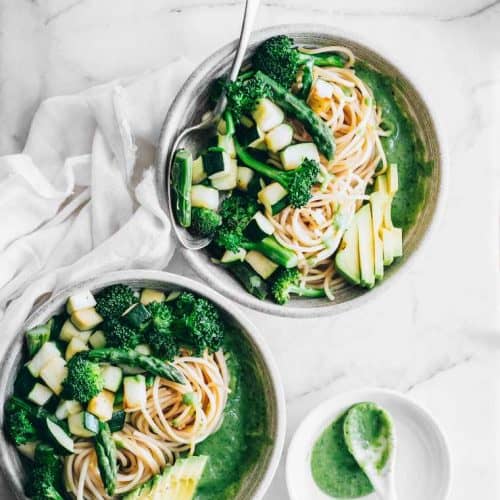 overhead of two bowls of hummus pasta with a spoon in one of them.