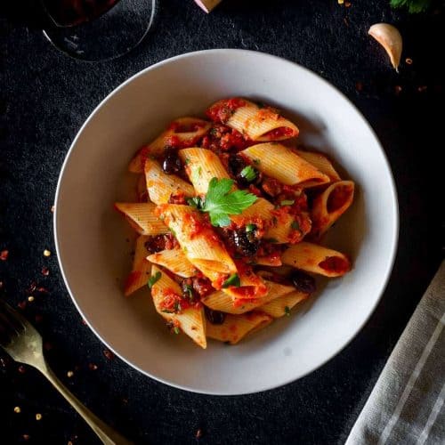 overhead of pasta with puttanesca sauce in a bowl.