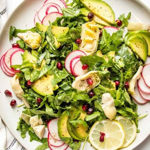 overhead of lemony arugula salad on a white plate.