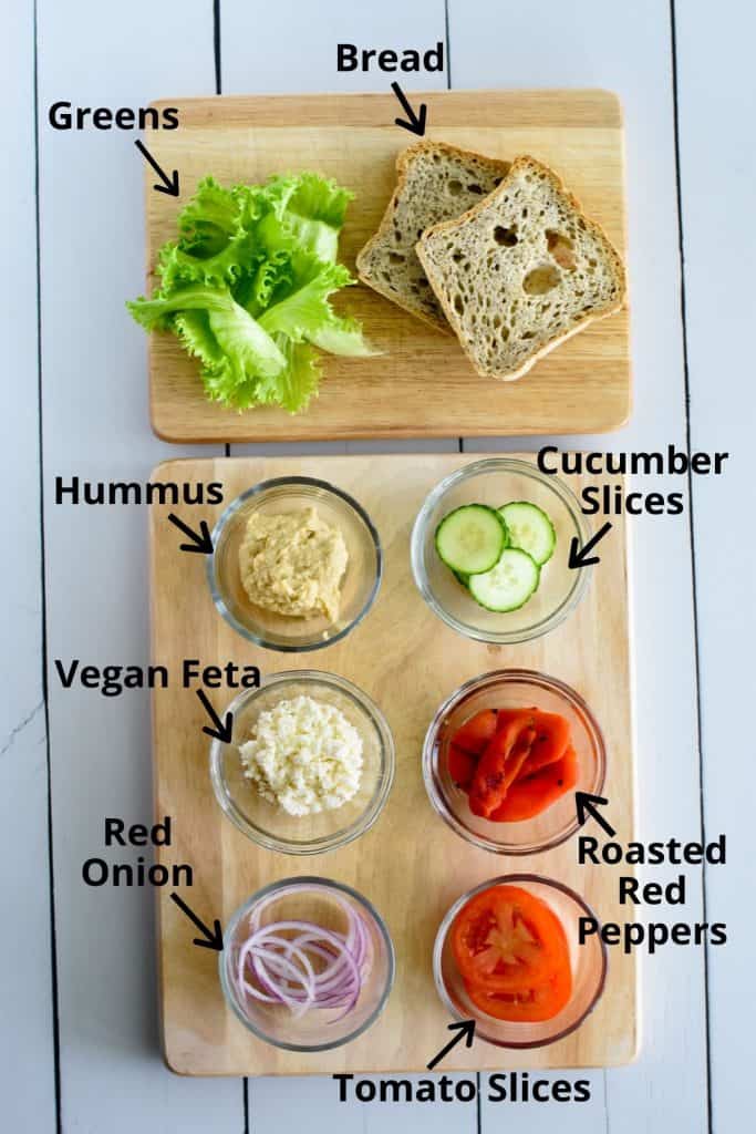 ingredients to make panera mediterranean veggie copycat sandwich on a wooden board with labels.