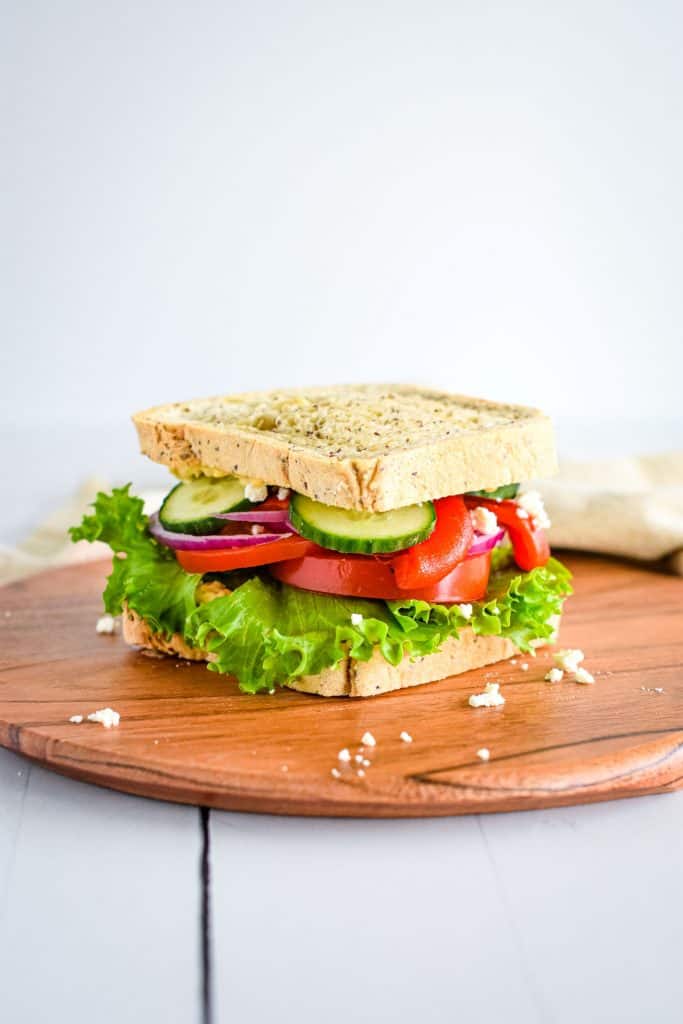 front view of copycat Panera Mediterranean veggie sandwich on a wooden board.