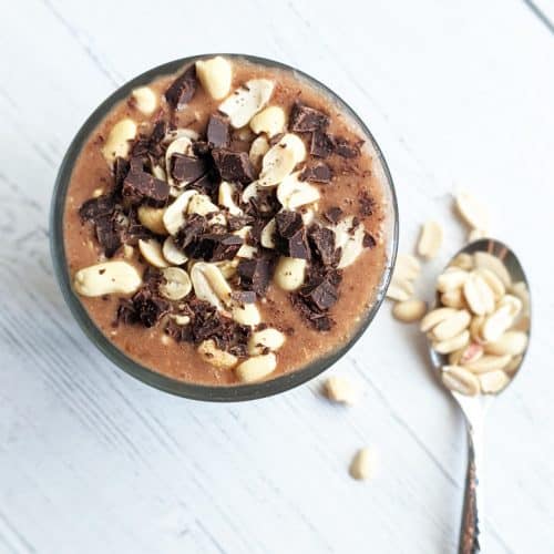 overhead shot of Snickers overnight oats with spoon of peanuts next to it.