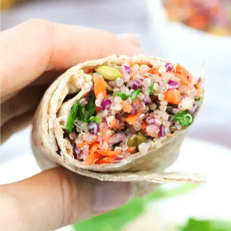 holding a half of a quinoa veggie wrap.