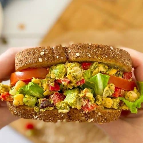 hands holding chickpea salad sandwich.