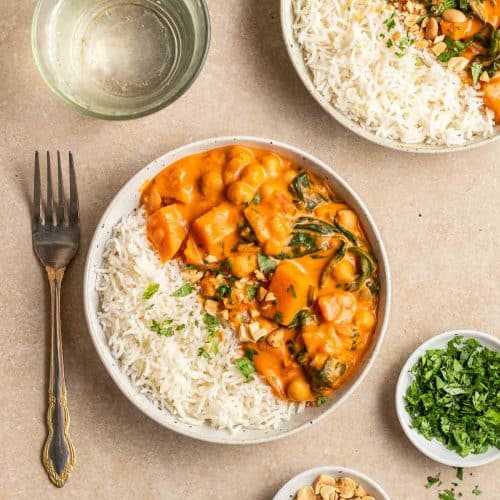 overhead shot of sweet potato chickpea curry with rice in a white bowl.