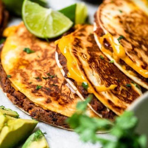 three cheesy black bean tacos on paper.