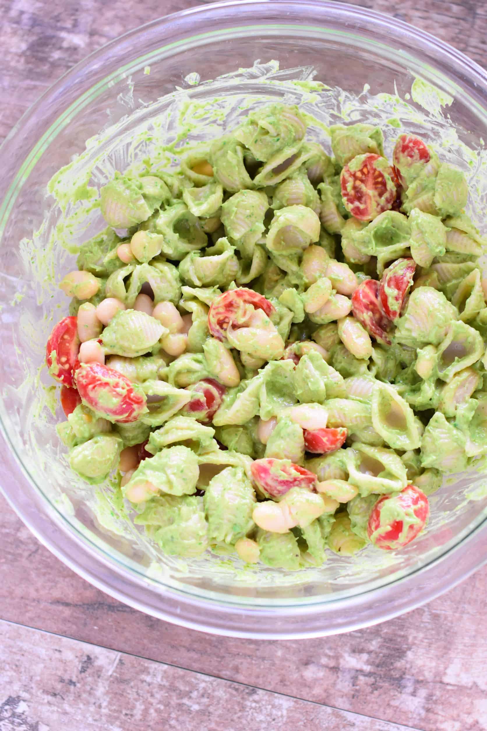 tomatoes and cannellini beans mixed into the pasta in the mixing bowl.