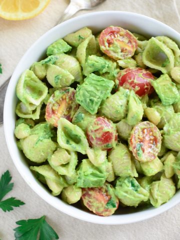 overhead of pasta salad in a white bowl with garnish around it.