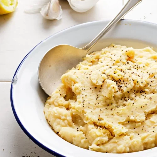 butter bean mash in a white bowl with a spoon in it.