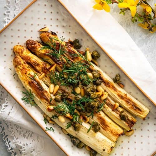 overhead of roasted white asparagus on a small serving platter.