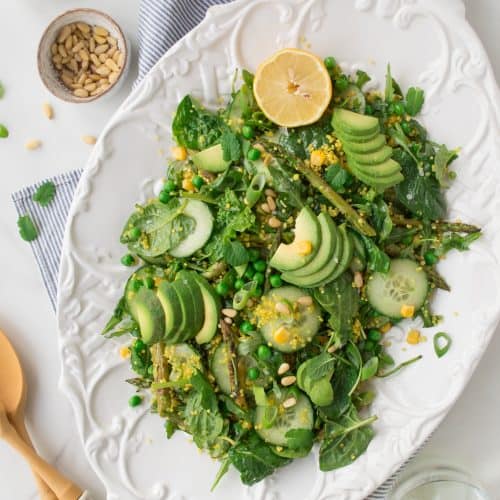 overhead of spring green salad on a white serving dish.