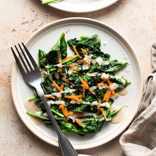 overhead of vegan spinach salad on a plate with a fork on it.