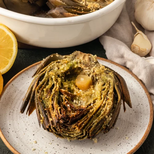 roasted artichoke on a white plate.