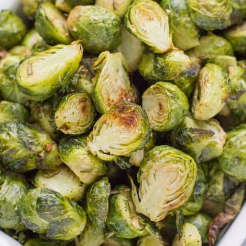 overhead of roasted brussels sprouts in white casserole dish.