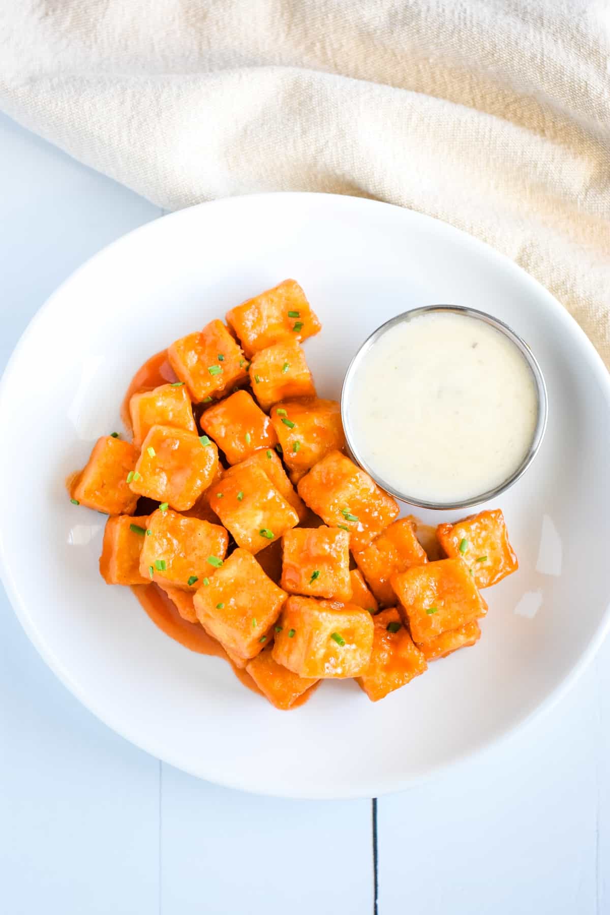 Tofu in buffalo sauce on a white plate.