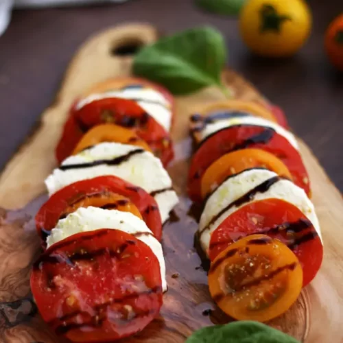 Classic Insalata Caprese Tomato Mozzarella Salad on a Wooden board.