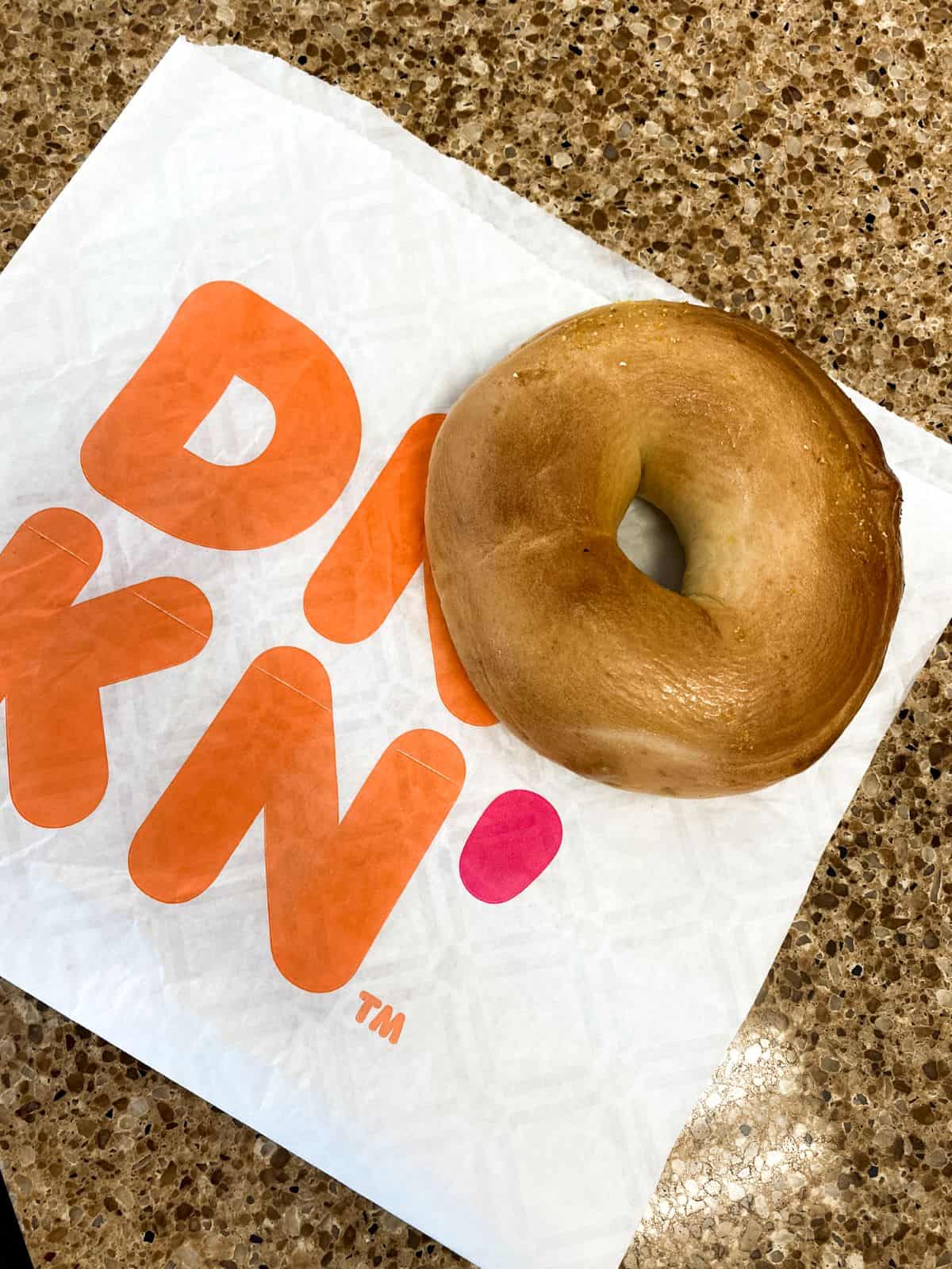 Dunkin' Donuts plain bagel on bag.