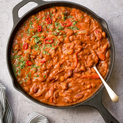 3 bean chili in a frying pan with a spoon.