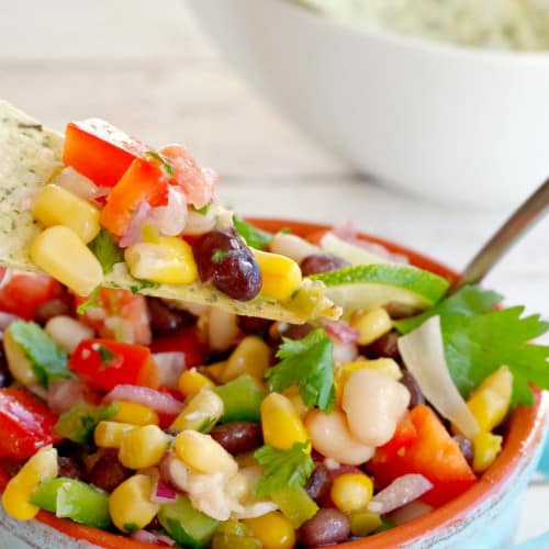 Cowboy Caviar Dip in a bowl with dip on a chip.