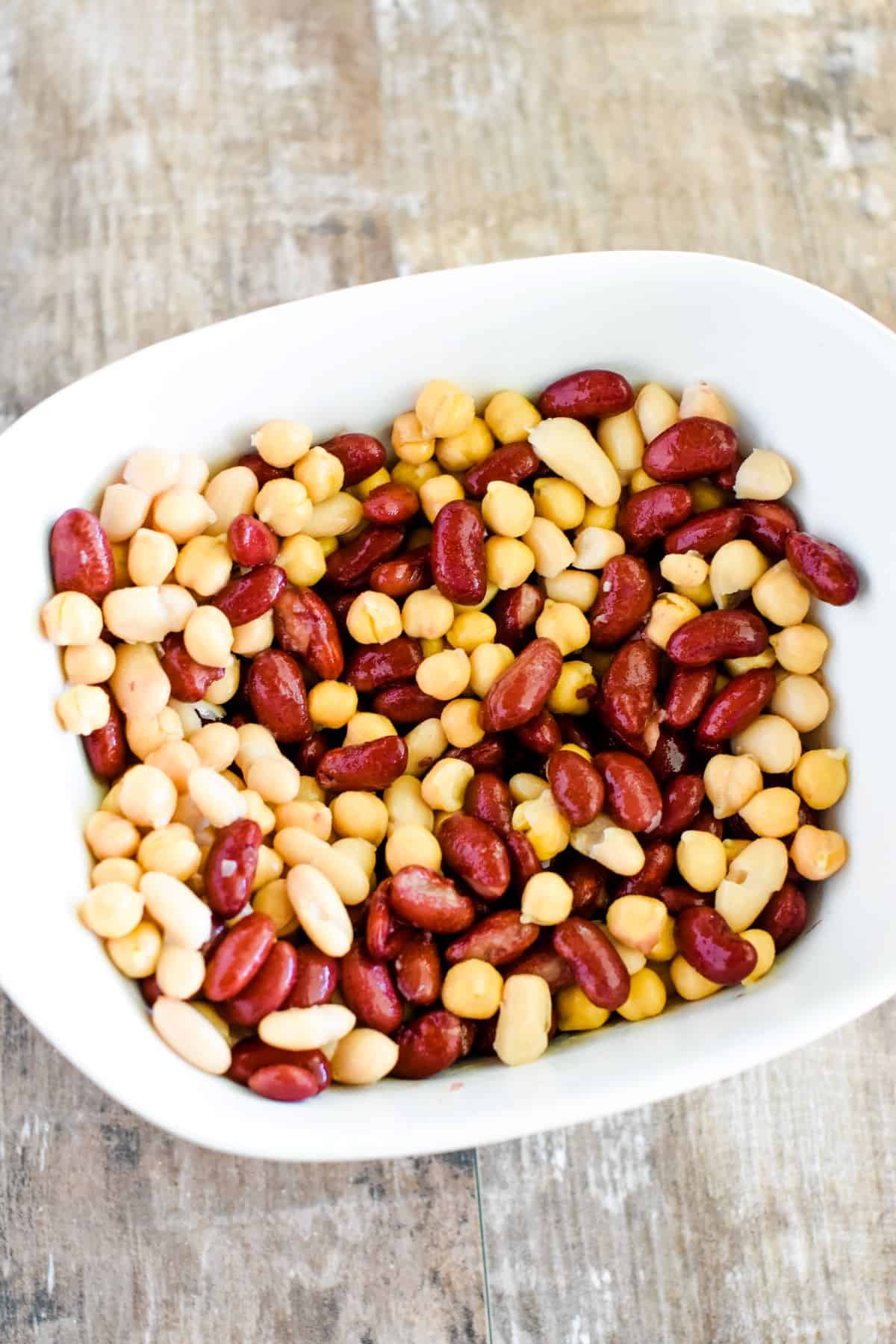 three kinds of beans mixed together in a white serving dish.