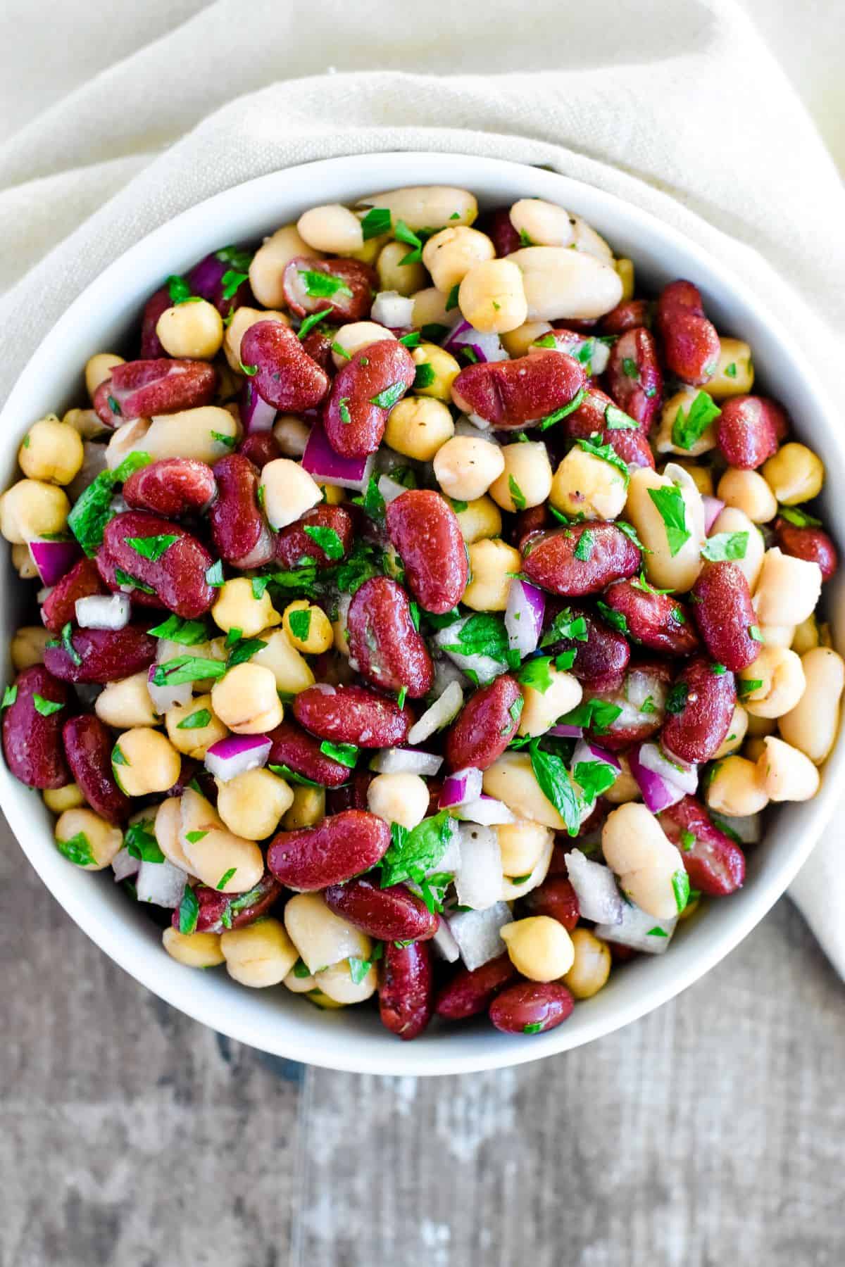 close-up overhead of three bean salad in a white bowl.