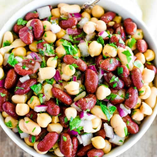 overhead of bean salad in a white bowl with a spoon in it.