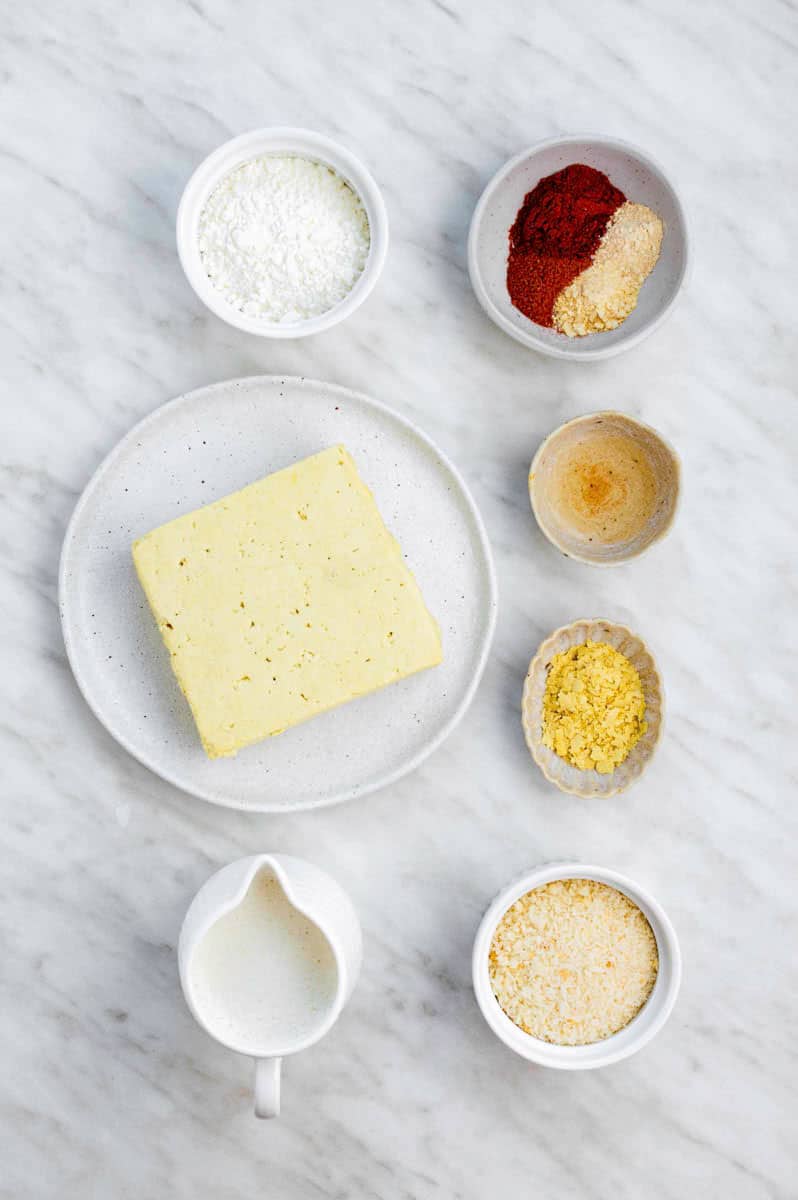 Gathered ingredients for making air fryer tofu nuggets placed on a marble countertop.