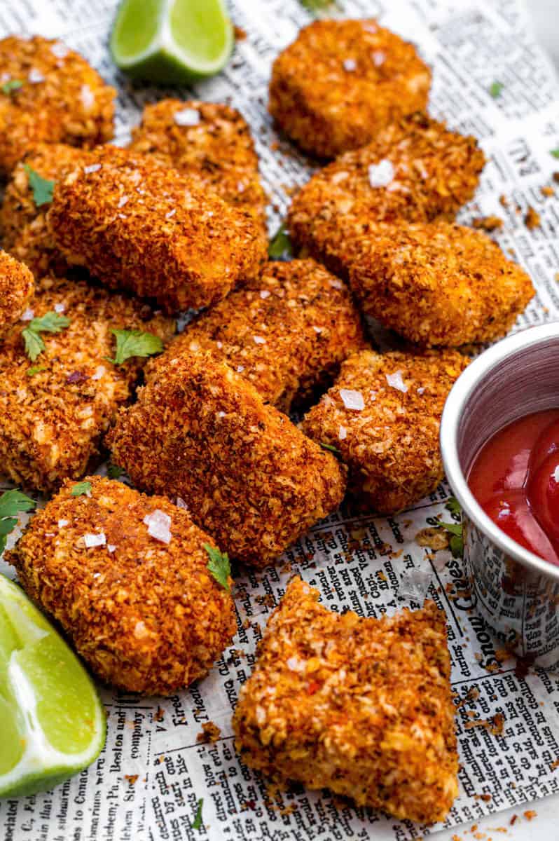 Air fryer tofu nuggets topped with sea salt and fresh cilantro next to a small bowl filled with ketchup.