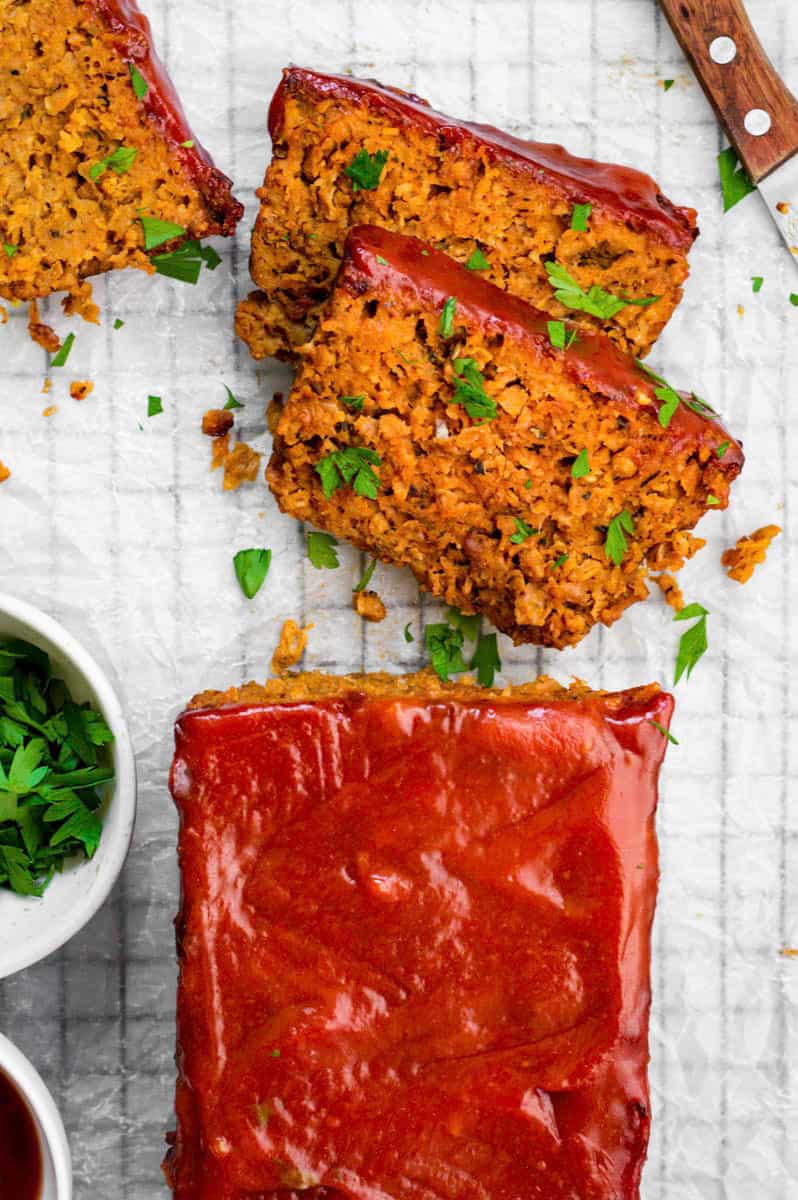 Three slices of Beyond meat meatloaf on parchment paper topped with chopped parsley.