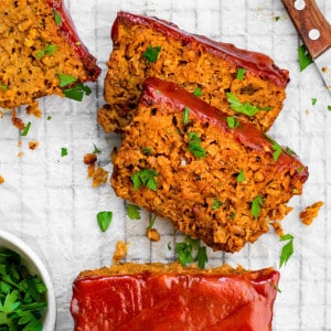 Three slices of Beyond meat meatloaf on parchment paper topped with chopped parsley.