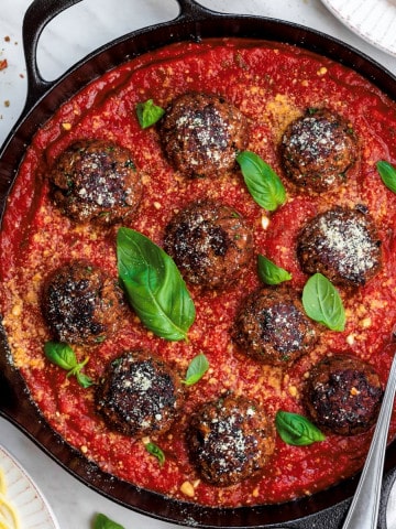 overhead close-up of meatballs in sauce with a spoon in it.