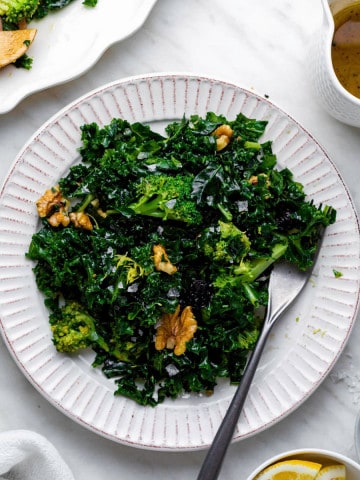 Chick fil a superfood kale salad served on a white plate with a fork on the side.