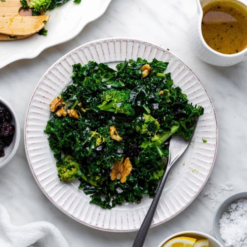 Chick fil a superfood kale salad served on a white plate with a fork on the side.