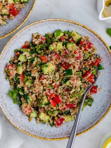 Copycat Costco Quinoa Salad served in a blue bowl with a fork placed on the right side of the bowl.