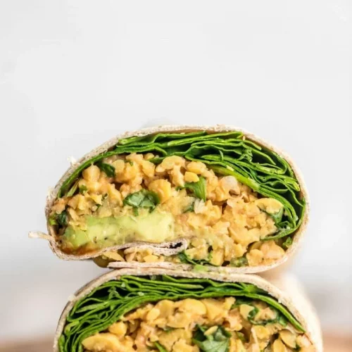 Vegan spicy chickpea wraps with avocado and spinach stacked on top of one another.