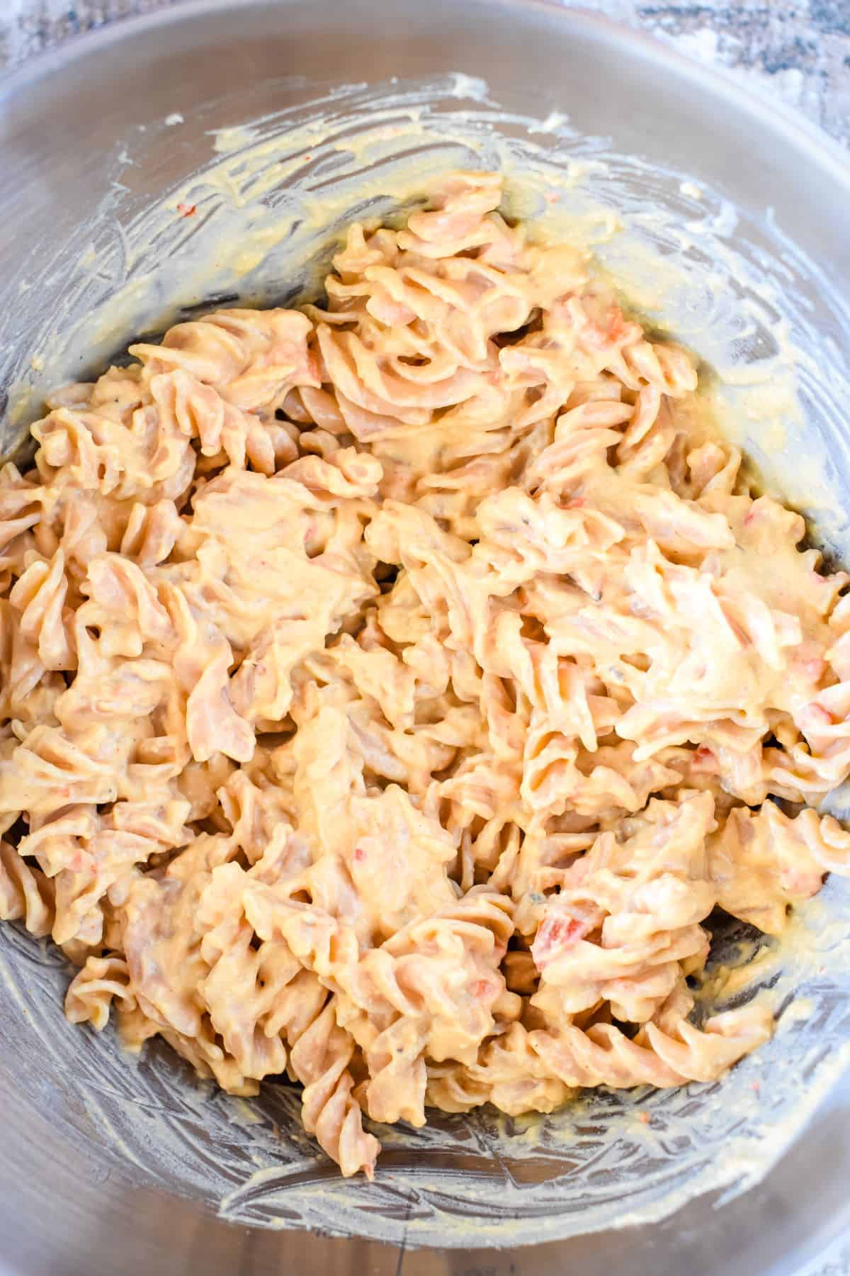 pasta in mixing bowl with hummus mixed in.