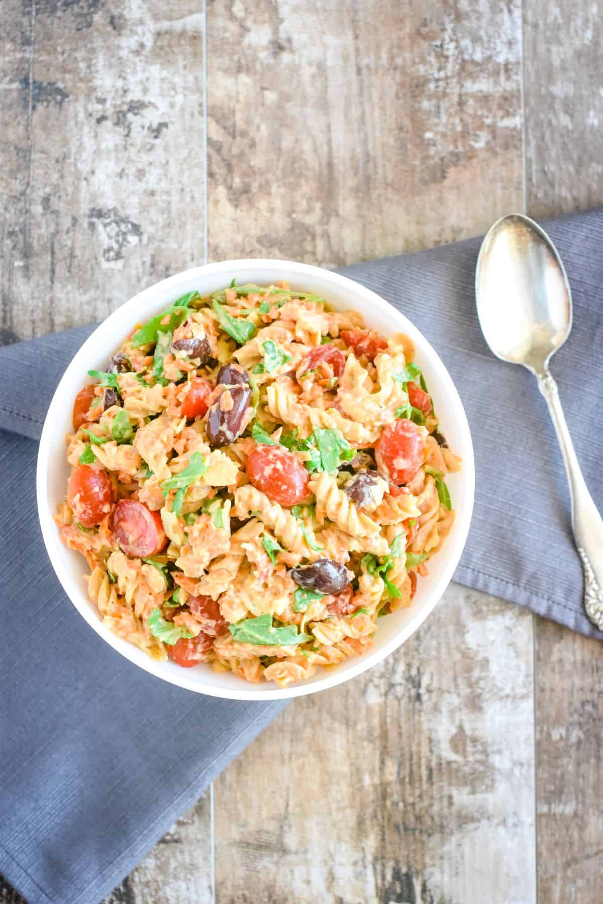 overhead of pasta salad in a bowl with a spoon next to it on a kitchen towel.