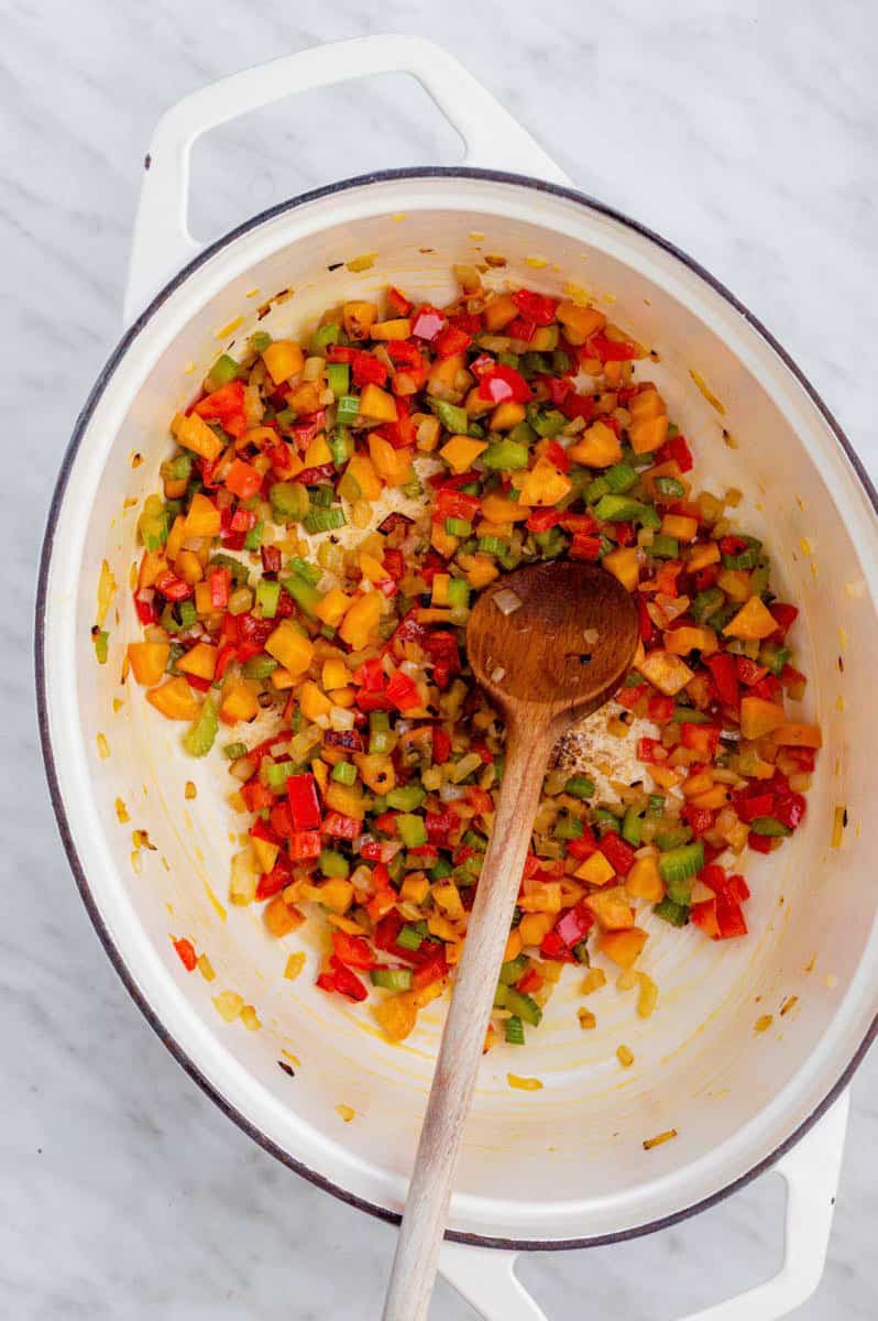 Sauteing vegetables in a white Dutch oven. 